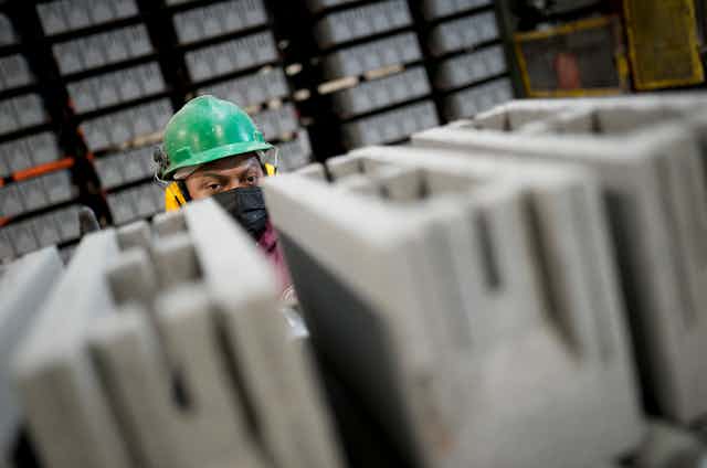 A worker in hard had peers over the top of newly produced cement blocks