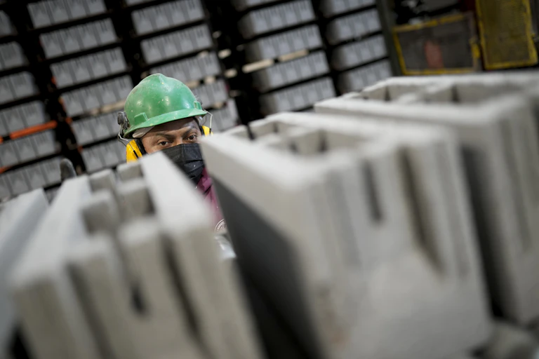 A worker in hard had peers over the top of newly produced cement blocks