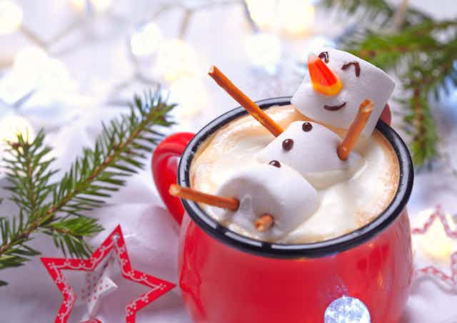 A snowman made of marshmallows in a mug of hot chocolate
