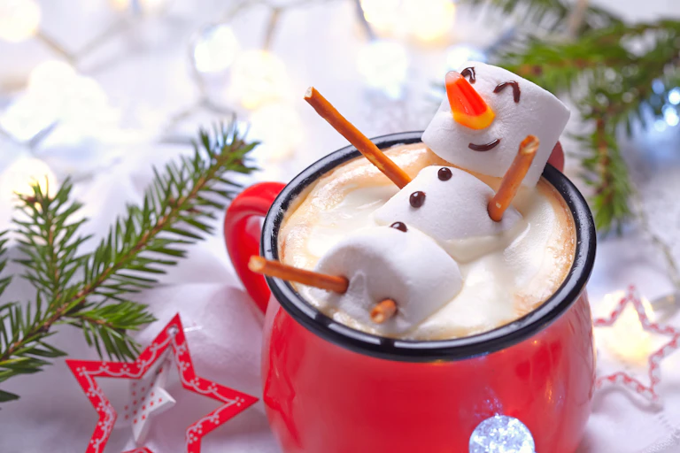 A snowman made of marshmallows in a mug of hot chocolate