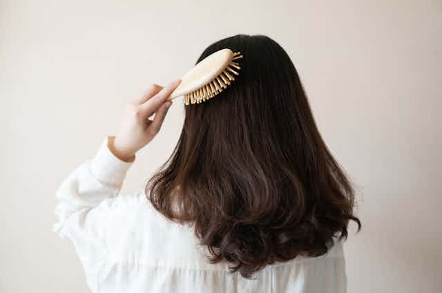 A person brushes their hair