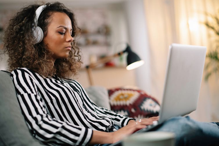 A woman with curly hair works on her computer.