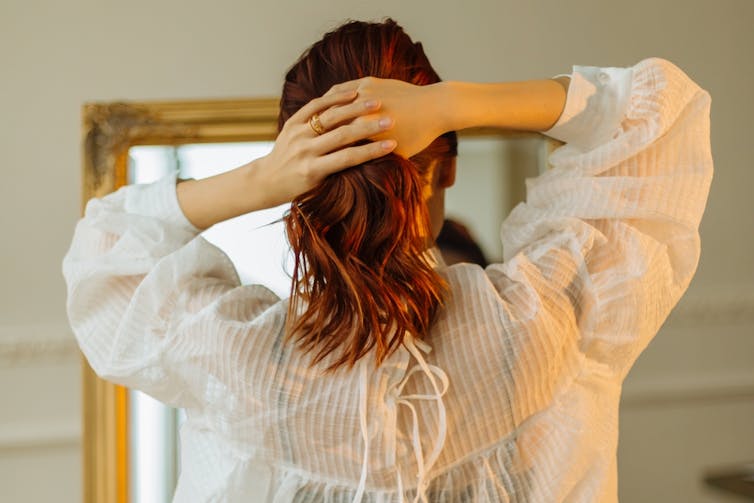 Woman with wavy hair looking in the mirror.