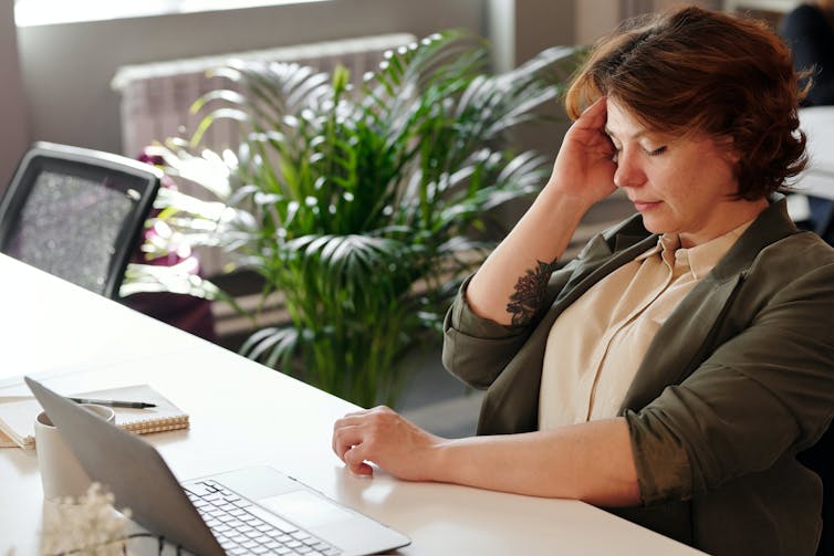 Woman sits at her desk, tired