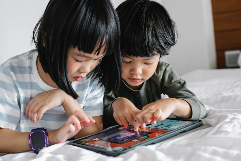 Two small children play on a tablet together.