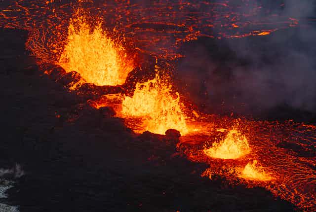 Glowing lava erupts through a series of ruptures, and flows out a glowing fan pattern.