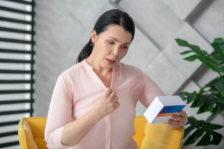 A woman looking at a box of hormone replacement therapy tablets.