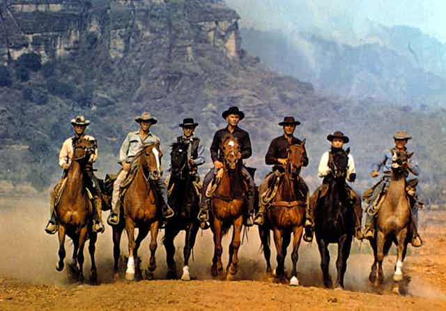 Seven cowboys on horseback.