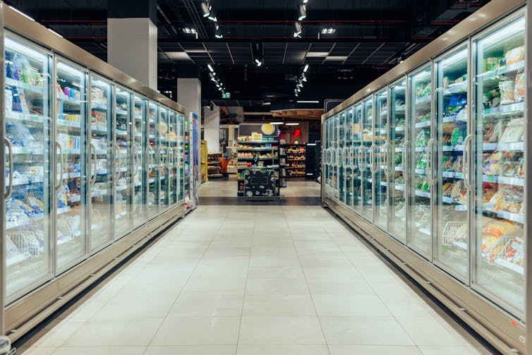 An empty supermarket aisle with freezers full of different products