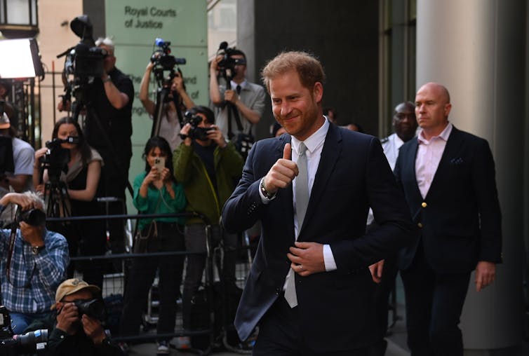 Prince Harry gives a thumbs up to the cameras outside the Royal Courts of Justice.