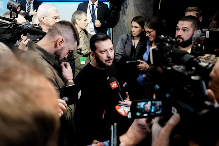 Ukrainian president Volodymyr Zelensky speaks to the press, surrounded by photographers.
