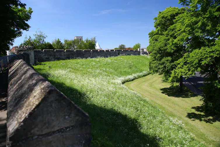 Medieval city walls and sloping grass.