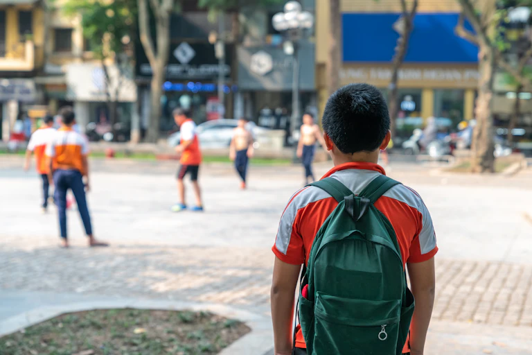 Boy watching as others play football