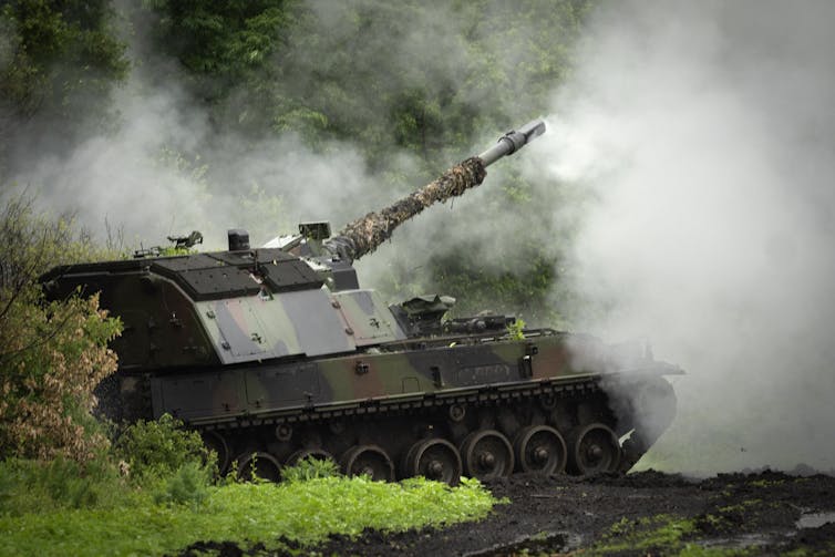 A large tank fires artillery. Smoke surrounds it.