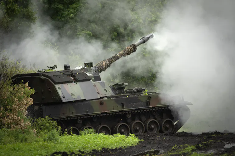 A large tank fires artillery. Smoke surrounds it.