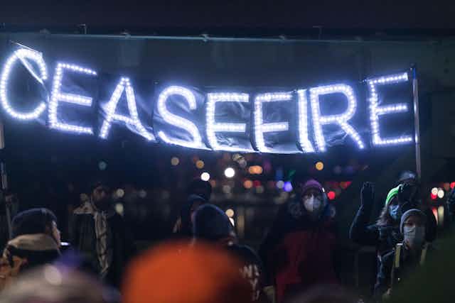 Protesters hold a banner saying: ceasefire.