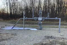 Gas leaks from pipes against a forested background.