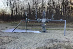 Gas leaks from pipes against a forested background.