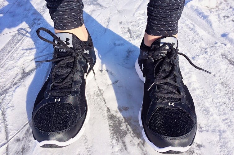 A runner's shoes stand in the snow.