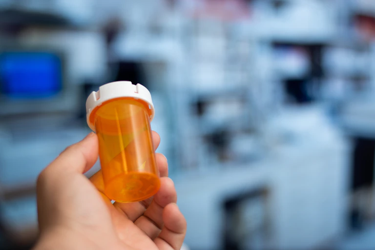 A person holds an empty prescription bottle.