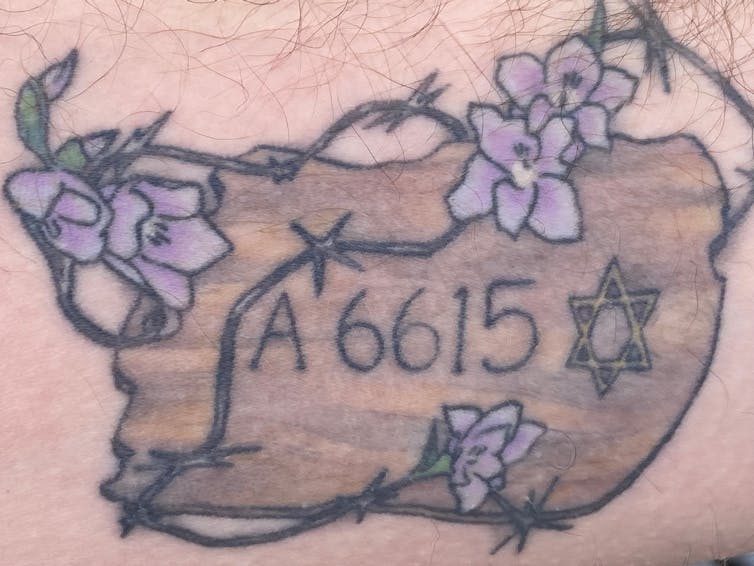 A tattoo of an Auschwitz concentration camp number surrounded by flowers.