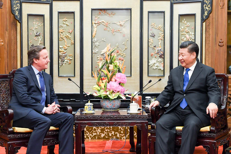 David Cameron sitting with Xi Jinping.