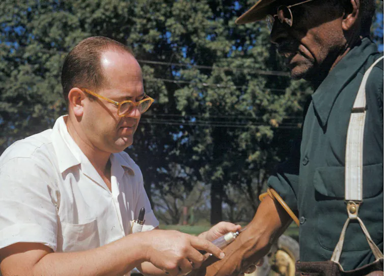 A Black man has blood drawn by a doctor in Tuskegee, Alabama.