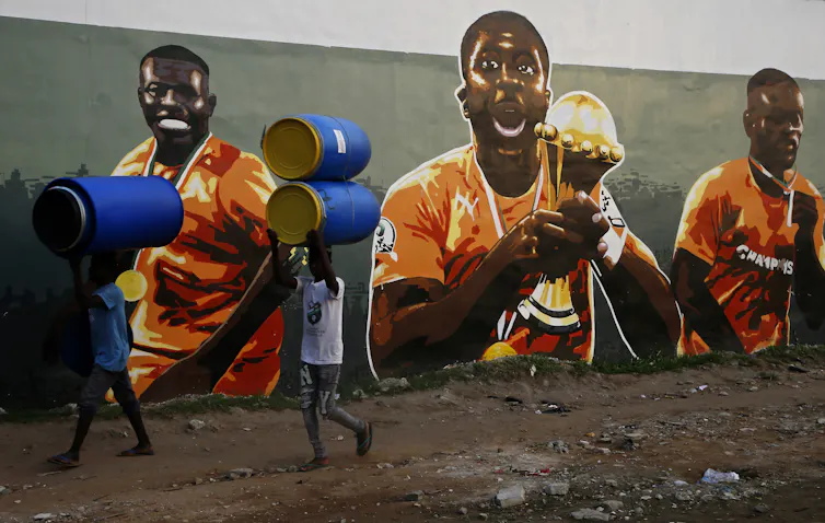 People walk past a football mural.