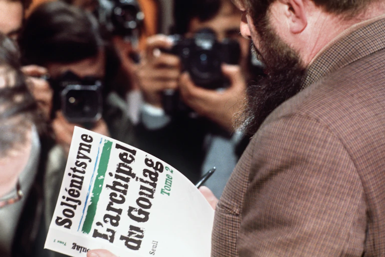 Alexandre Soljénitsyne tenant dans ses mains un exemplaire du tome 2 de « L'Archipel du Goulag » devant des photographes
