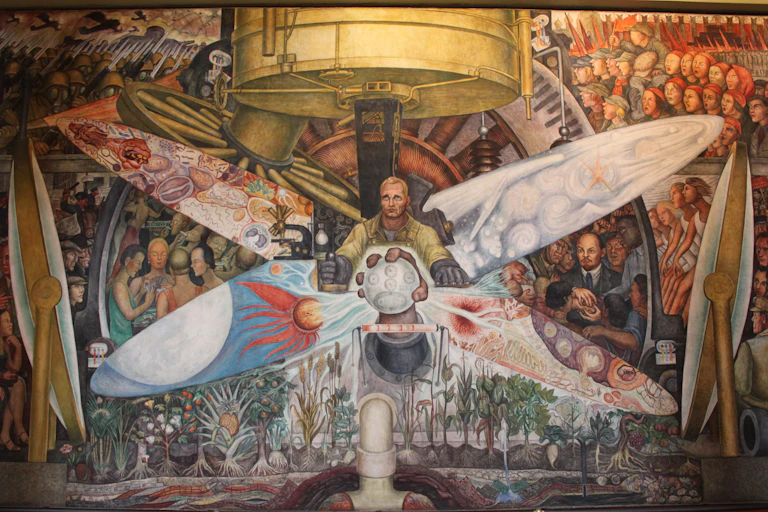 Inmenso mural que retrata a un hombre sosteniendo un engranaje rodeado de gente representando el capitalismo a un lado y el socialismo al otro.