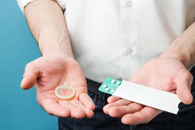 Un homme dont on ne voit que le buste tient dans une de ses mains un préservatif et, dans l'autre, une plaquette de pilules contraceptives.