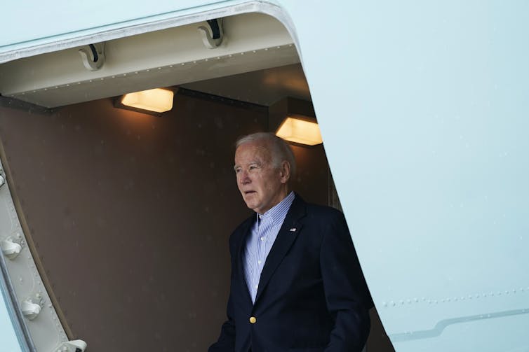 An older man looks out the entrance of a large aircraft.