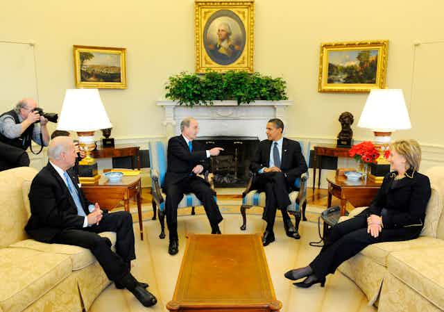 Joe Biden, George Mitchell, Barack Obama, Hillary Clinton sitting in the Oval Office, 2009