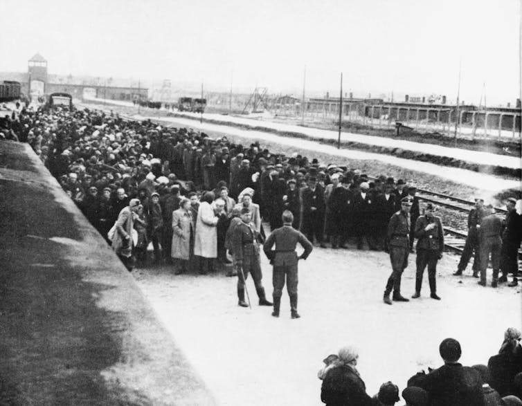 People taken prisoner by Nazis standing on a train platform in the Auschwitz concentration camp.