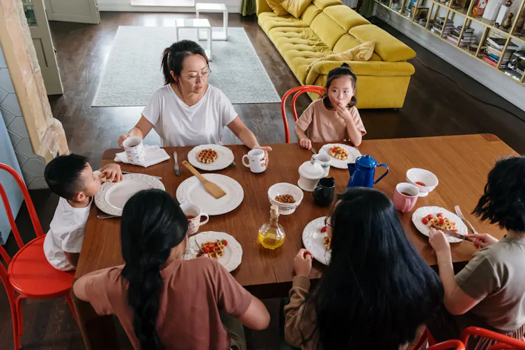 A family seen seated at a table eating a meal.