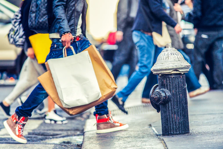 People crossing a street with shopping bags.