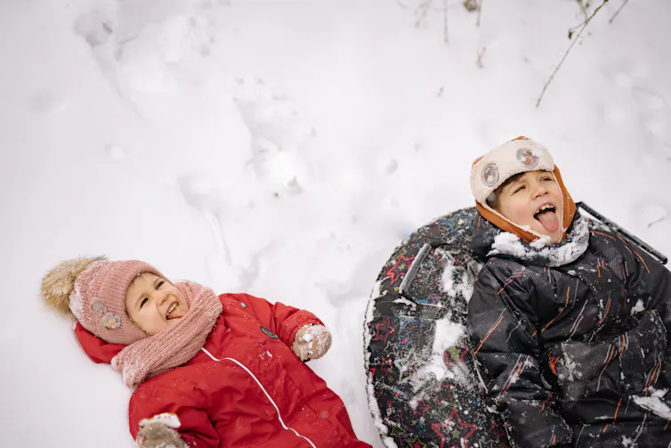 Two children seen playing in snow.
