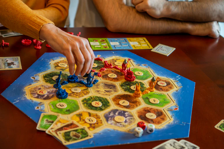 People playing the board game version of Catan.