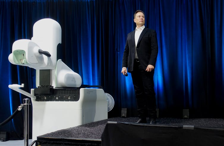 Suited man standing next to a brain imaging device.