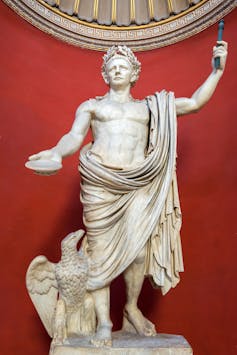 A statue of Emperor Claudius in a red-walled room.