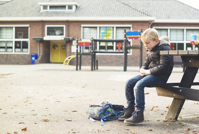 Child sitting on a bench looking glum