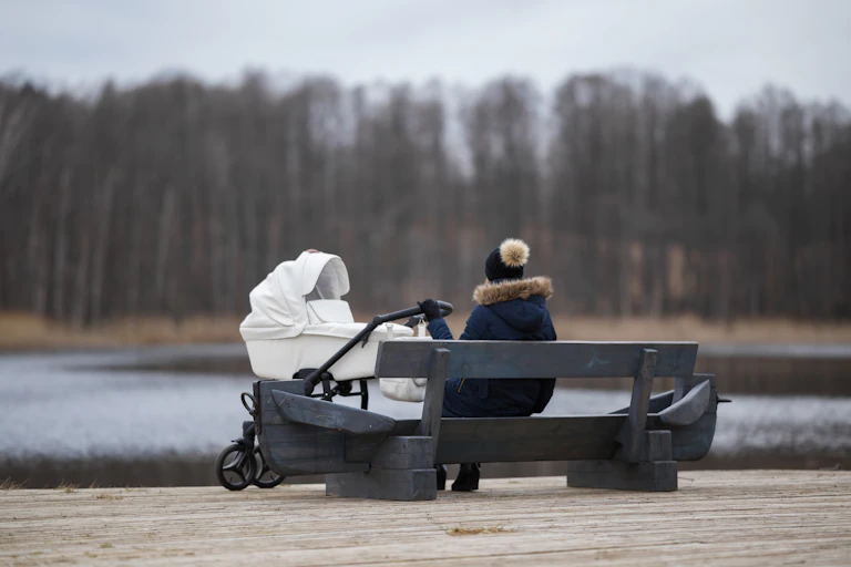 Woman with pram looks out over water