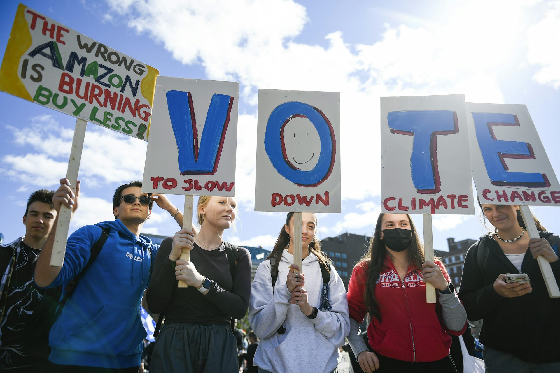 A row of young people hold signs calling for climate action.