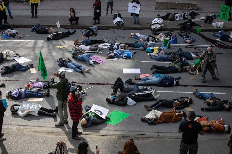 People lie on the ground pretending to be dead during a climate protest.