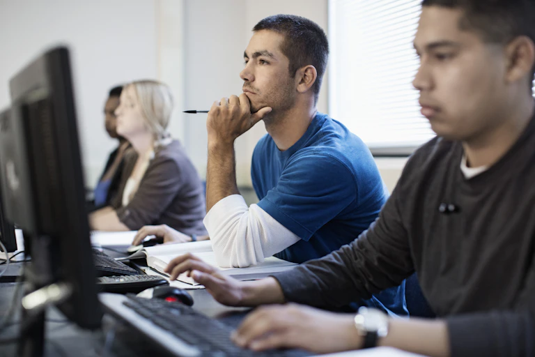 Four adult students sit at computers.