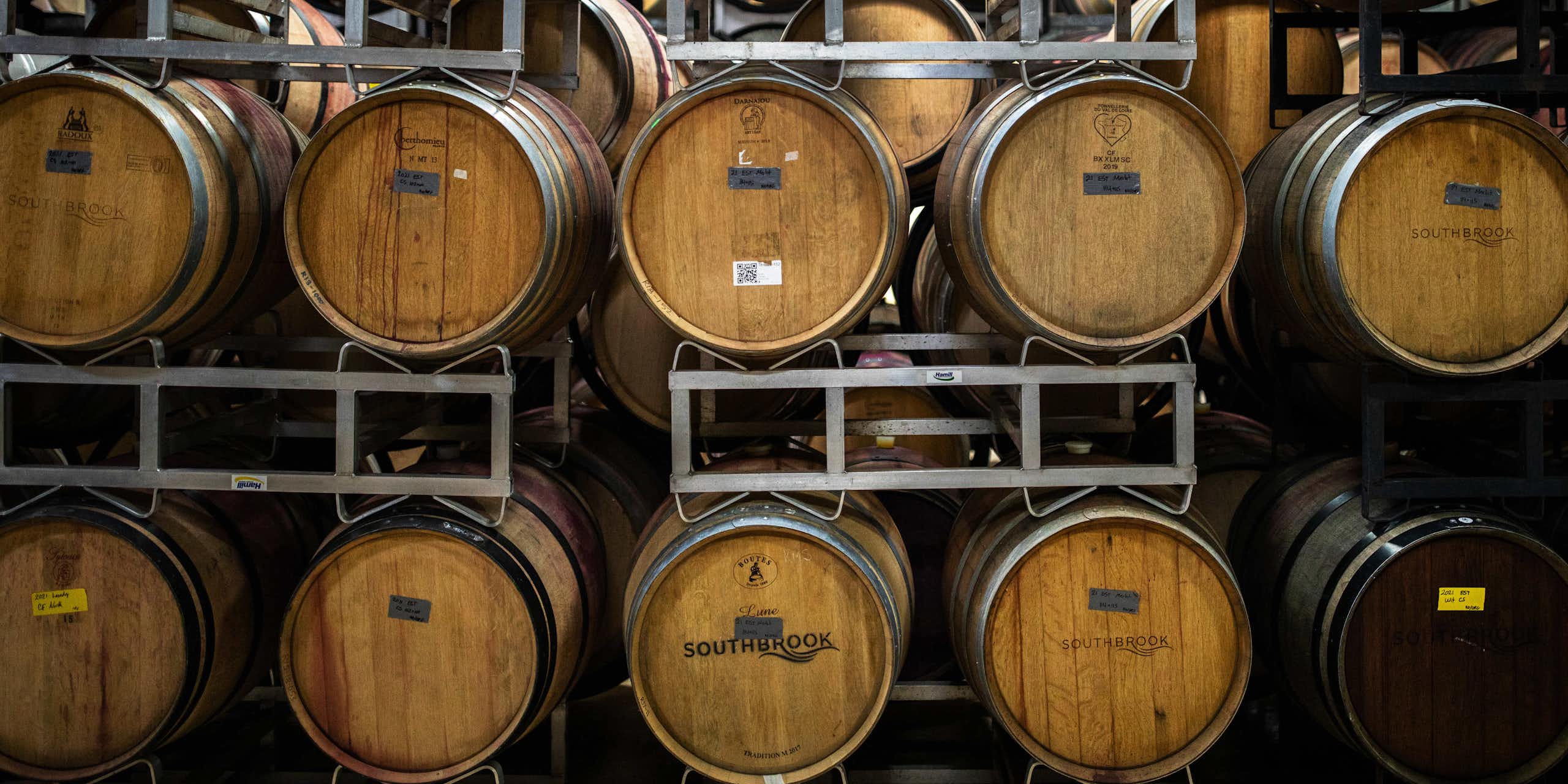 Barrels of wine are shown stacked in a cellar.