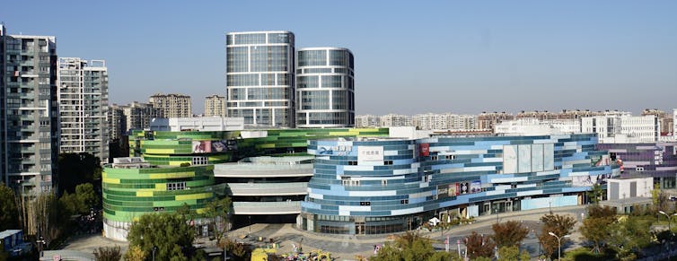 A curved modern building labeled Oasis, with towers in the background. Chinese shopping malls.
