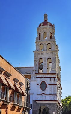 A white stone church tower against an azure sky.