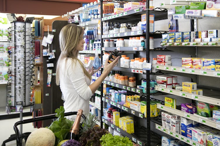 A woman in a drug store shops in the supplement aisle.