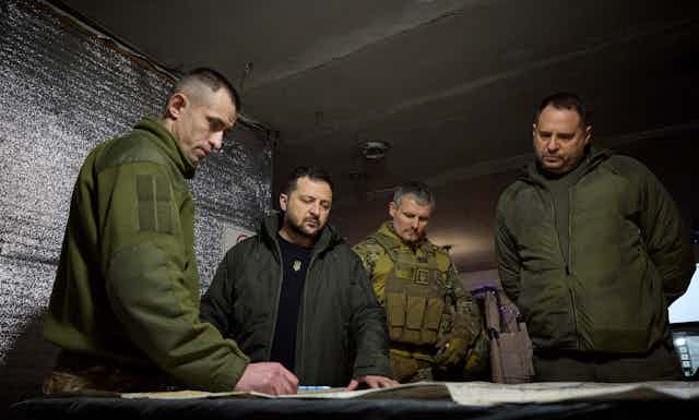 Ukrainian president Volodymyr Zelensky with aides looking at charts in a military bunker.